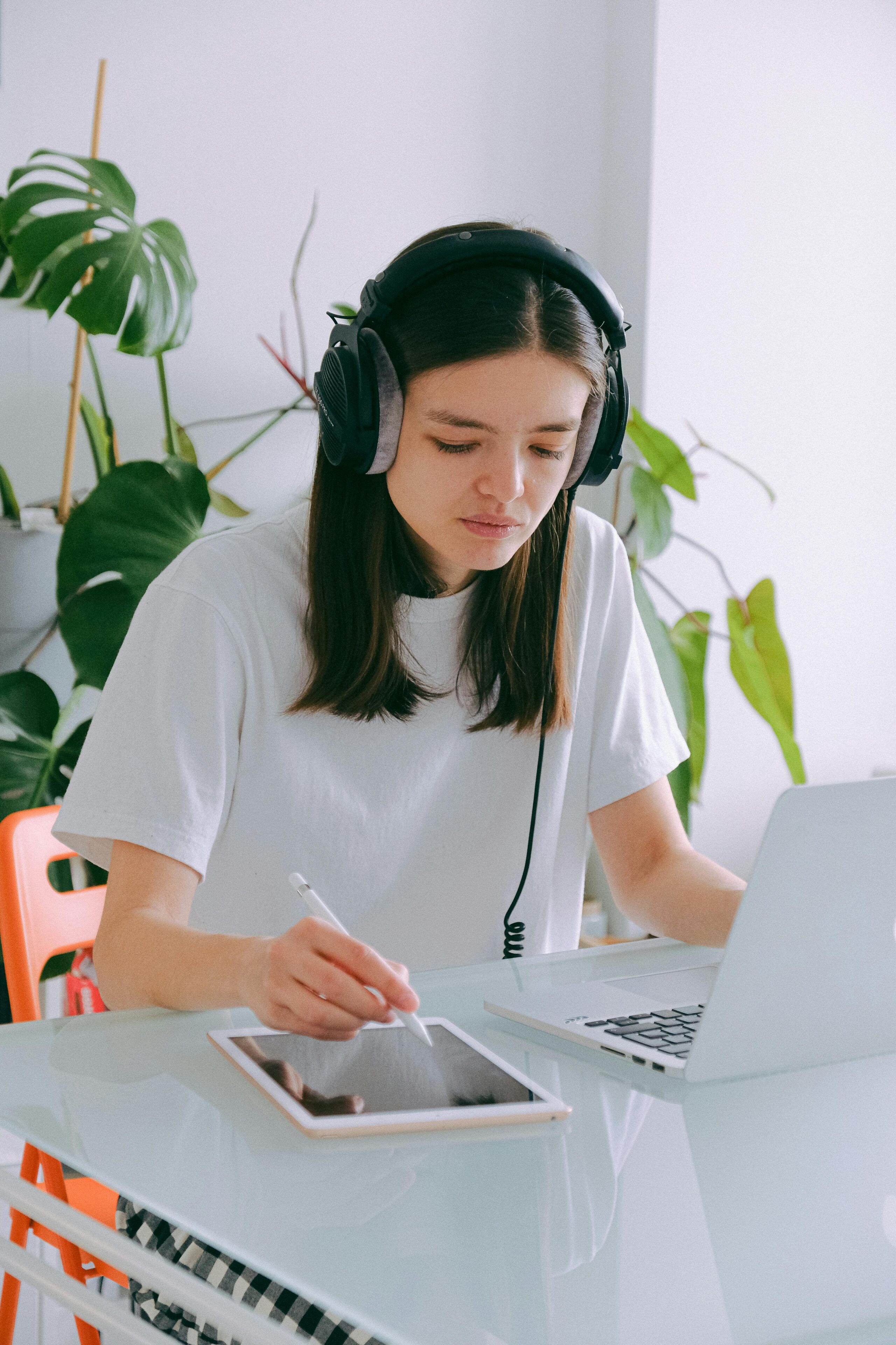 A bright, modern home office featuring a person working on a laptop, natural light, plants, and minimal distractions